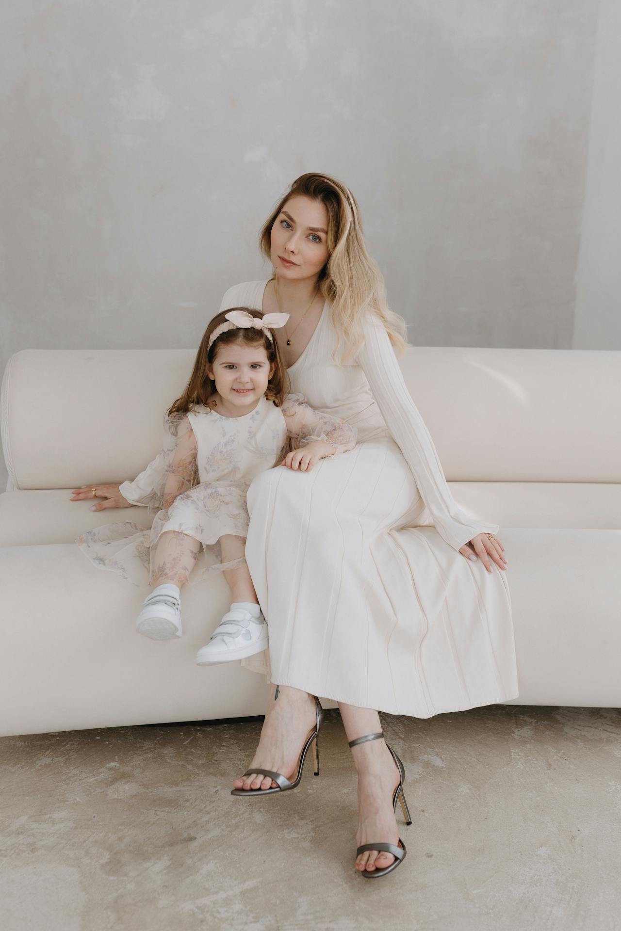Mother and Daughter in Dresses Sitting on Sofa