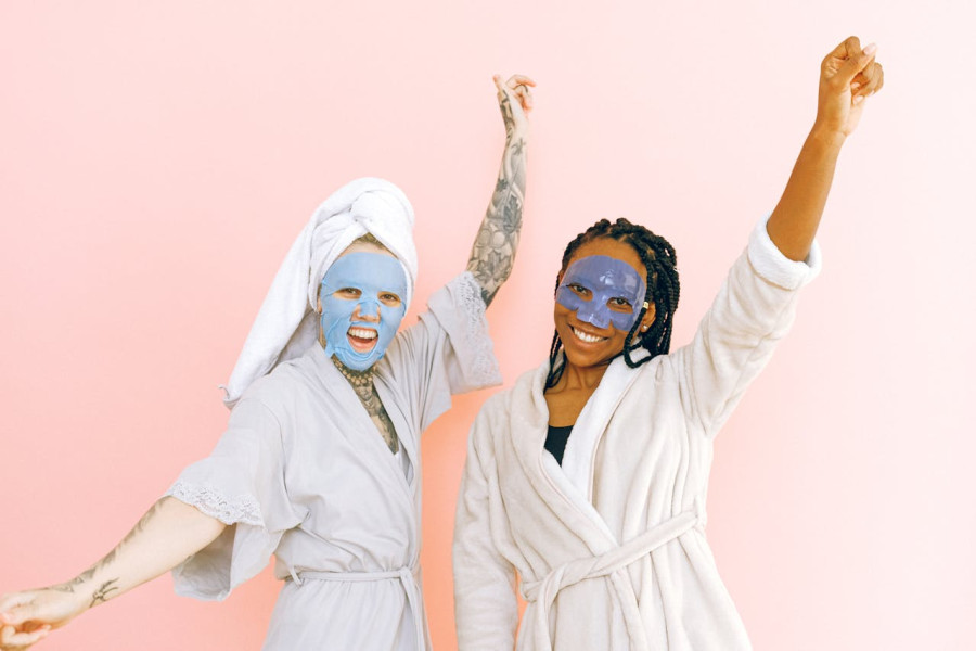 Content multiracial female friends in cosmetic masks raising hands